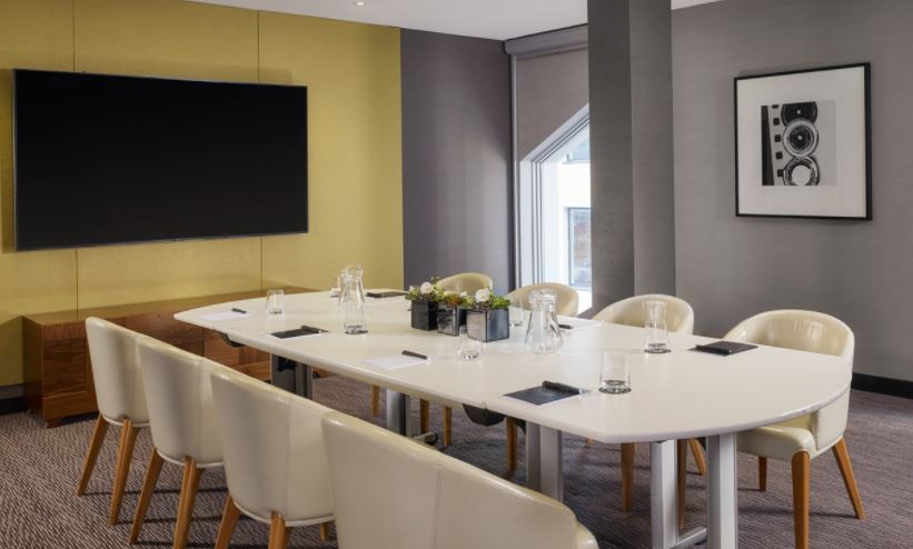 Modern meeting room with white table, ideal for corporate events and presentations.