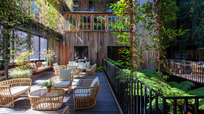 Outdoor event space with greenery and wooden elements, ideal for meetings and gatherings.