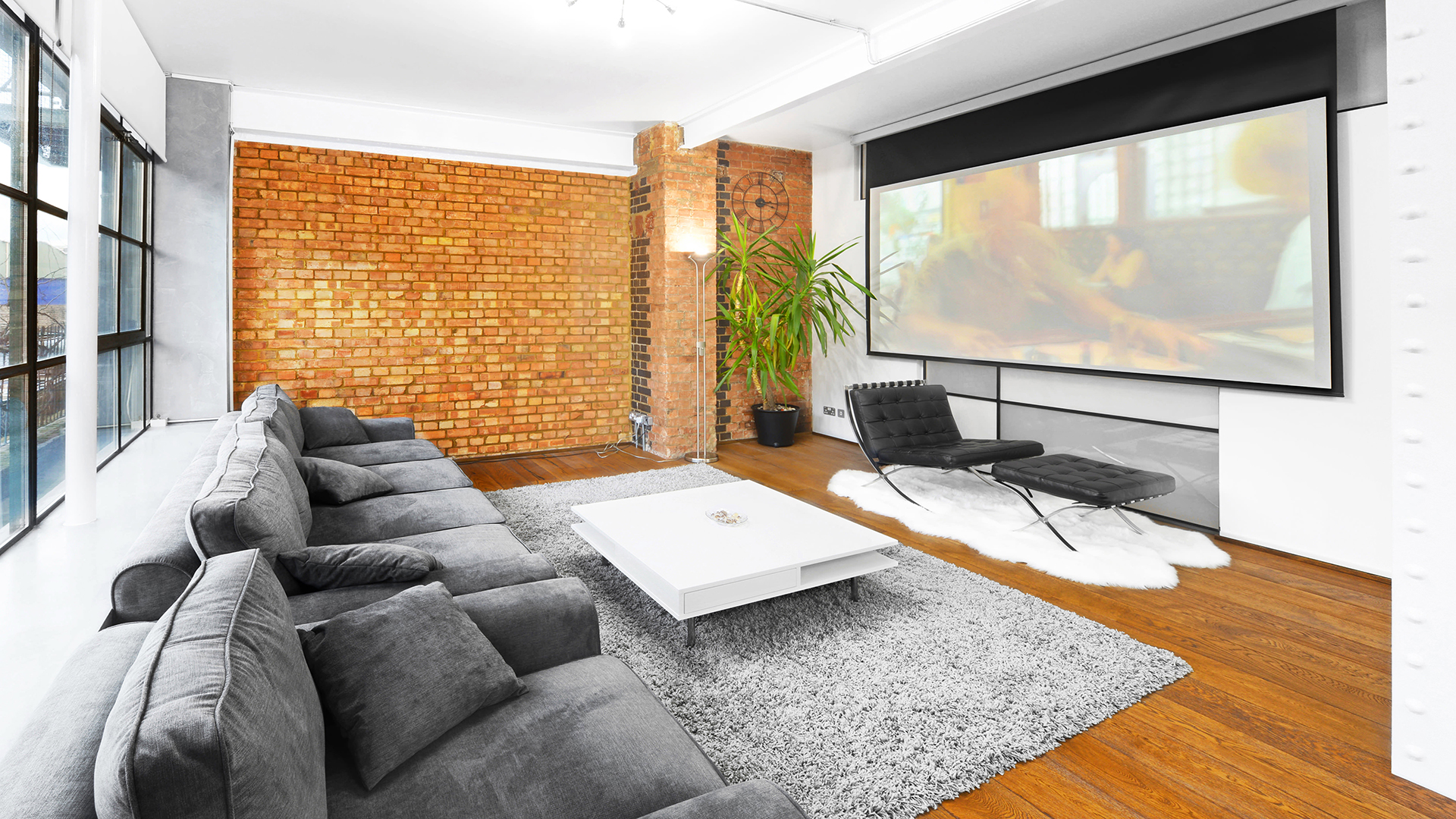 Modern lounge in S1 Apartment, featuring cozy seating and a large screen for meetings.