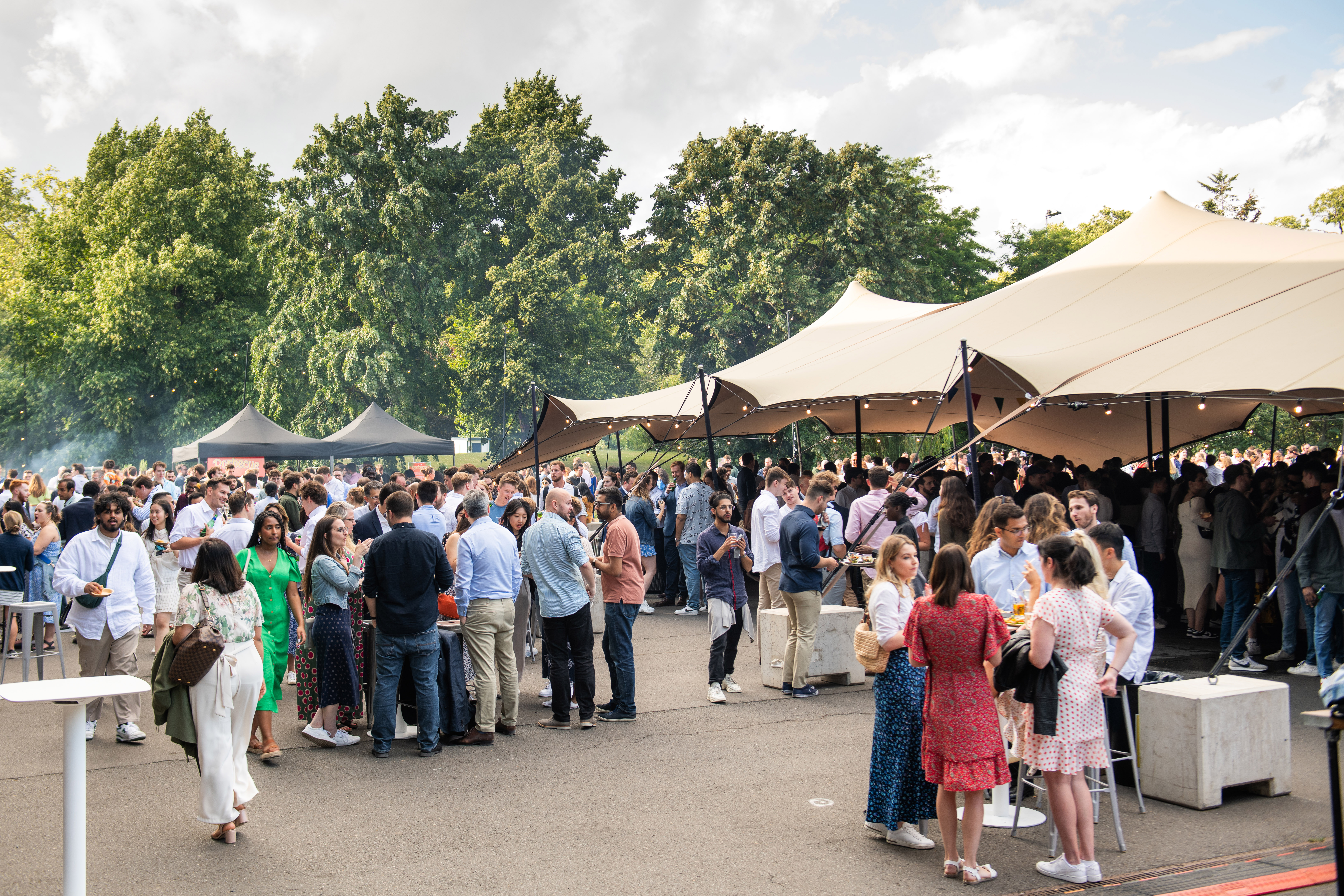 Vibrant outdoor summer event at Evolution London with stylish tents and engaged attendees.
