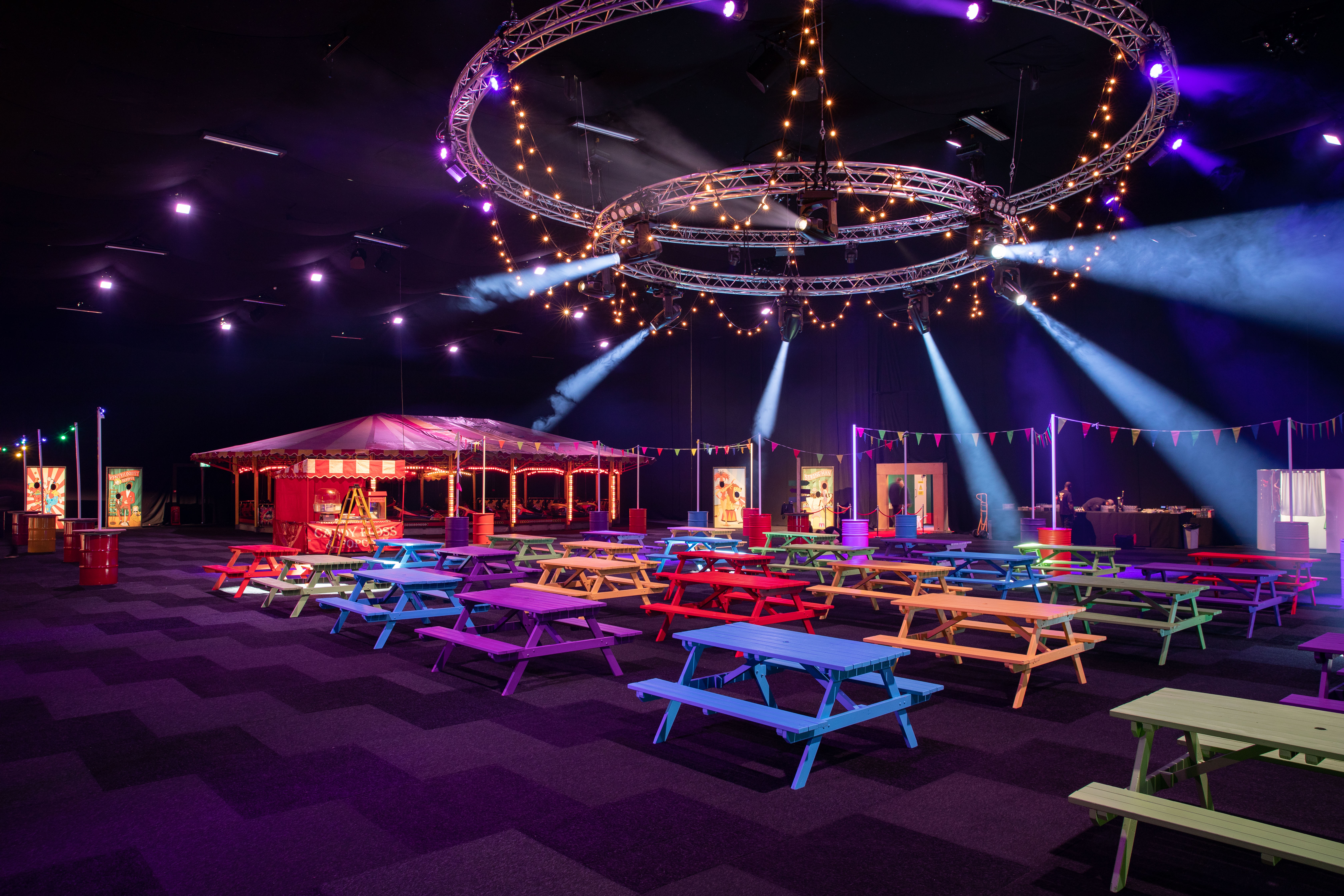 Vibrant carnival-themed event space with colorful picnic tables for summer gatherings.