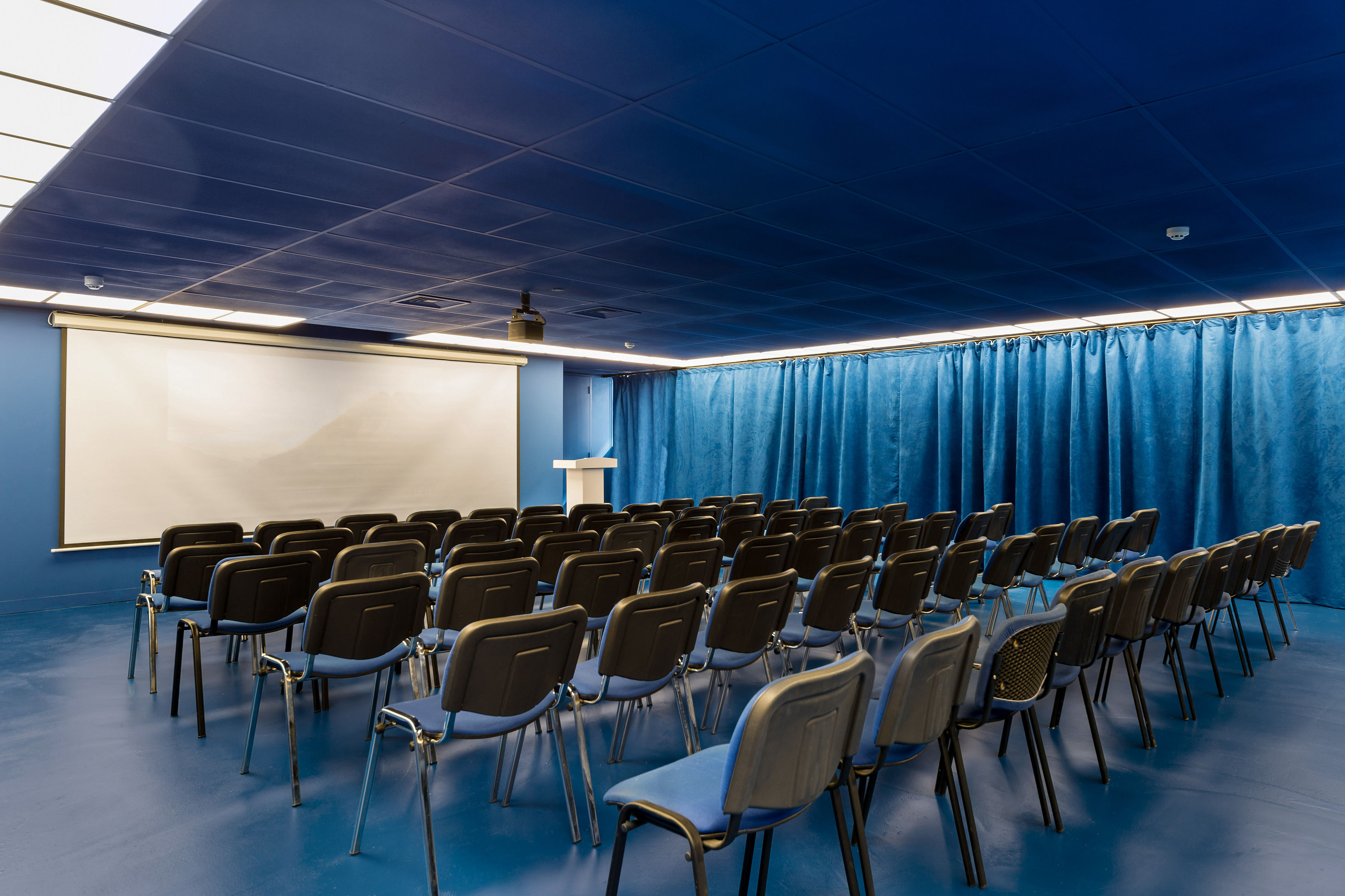 Modern blue event space with chairs for corporate meetings and presentations.