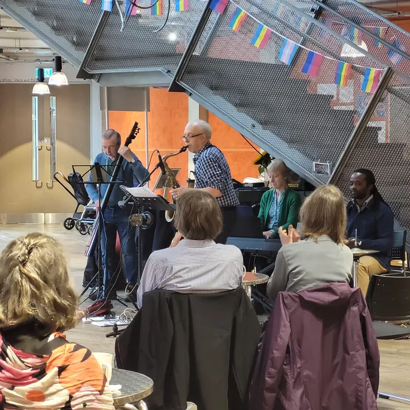 Lively Rose Cafe event with musicians, flags, and an engaged audience in Rose Theatre.