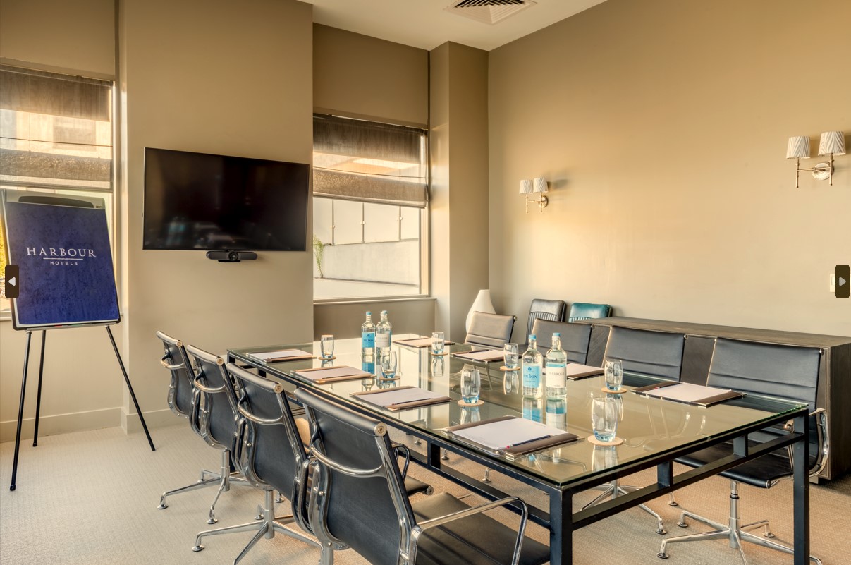 Modern meeting room at Guildford Harbour Hotel with glass table, ideal for workshops.