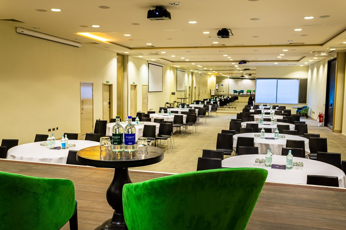 Spacious Guildford Harbour Hotel conference venue with round tables and modern decor.