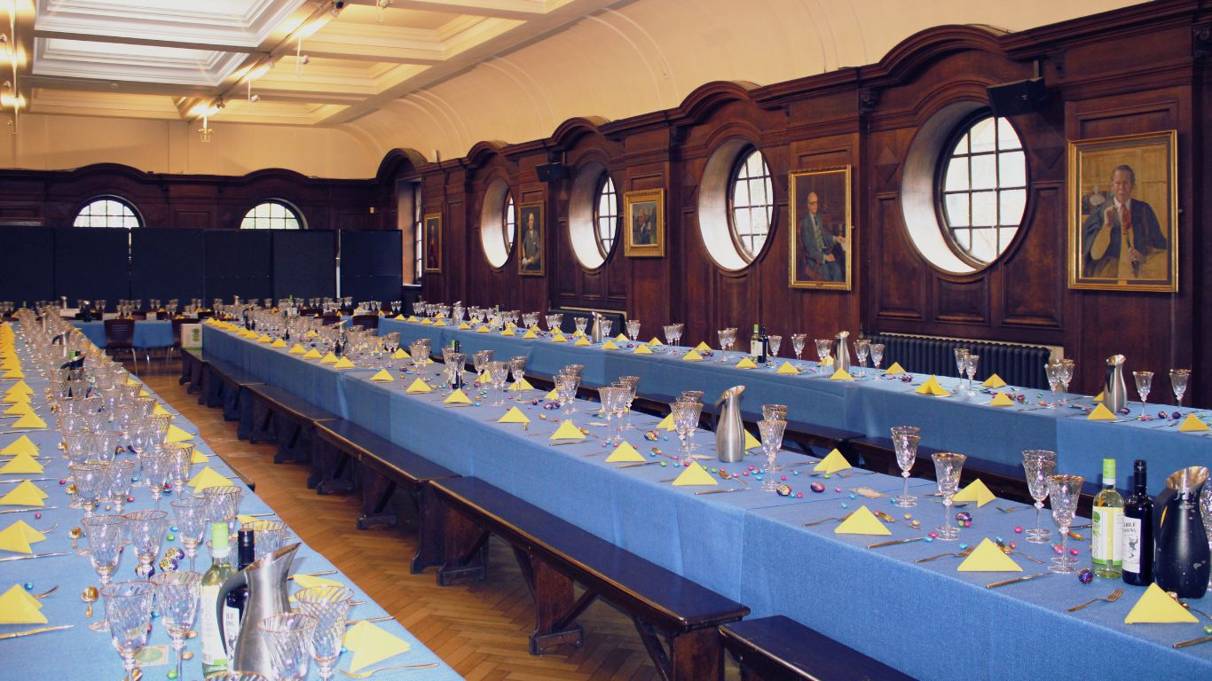 Banquet setup in UCS Venues' Refectory with blue tablecloths and elegant decor.