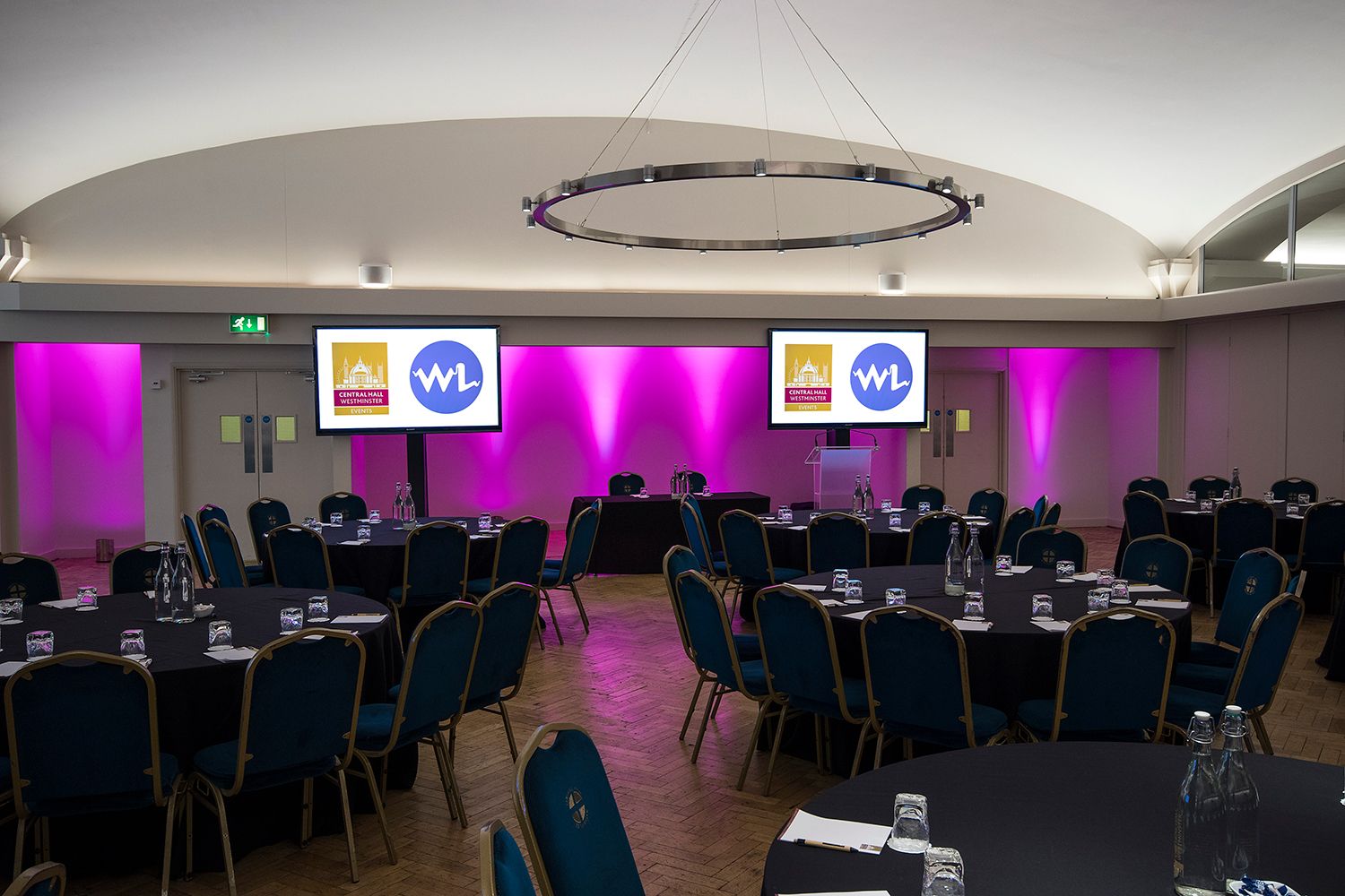 Aldersgate event space with round tables, purple lighting, ideal for corporate meetings.