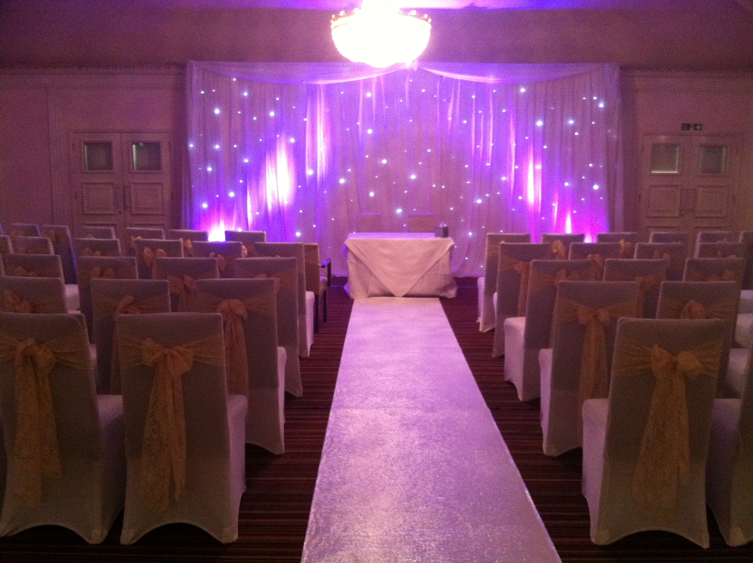 Elegant County Room at ABode Hotel, ideal for ceremonies with gold-sashed chairs.