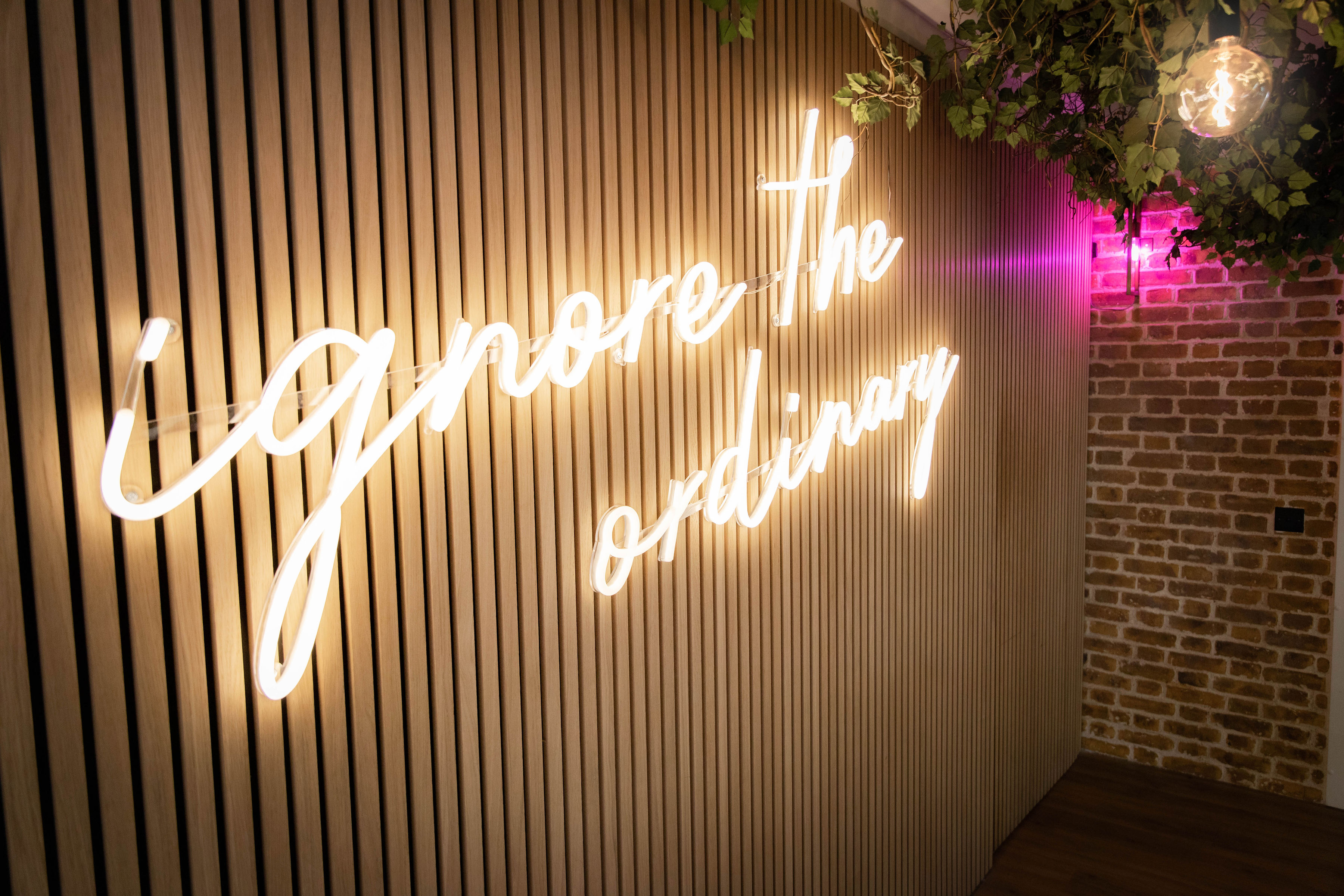 Stylish EC1 Campus venue with neon "ignore the ordinary" sign for creative events.