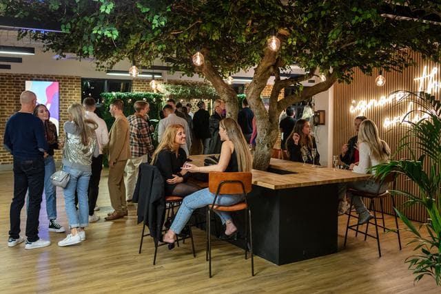 Vibrant EC1 Campus event space with casual seating and central tree for networking.