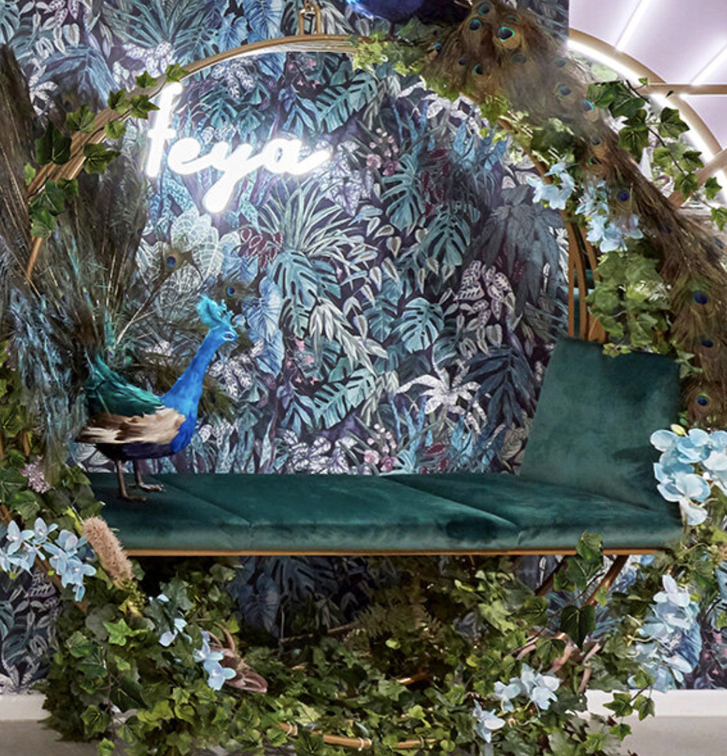 Tropical event backdrop with peacock and lush foliage for immersive photo opportunities.