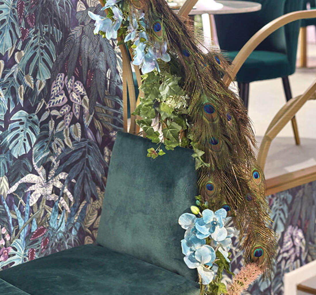 Elegant event space with lush greenery and peacock feathers for tropical celebrations.