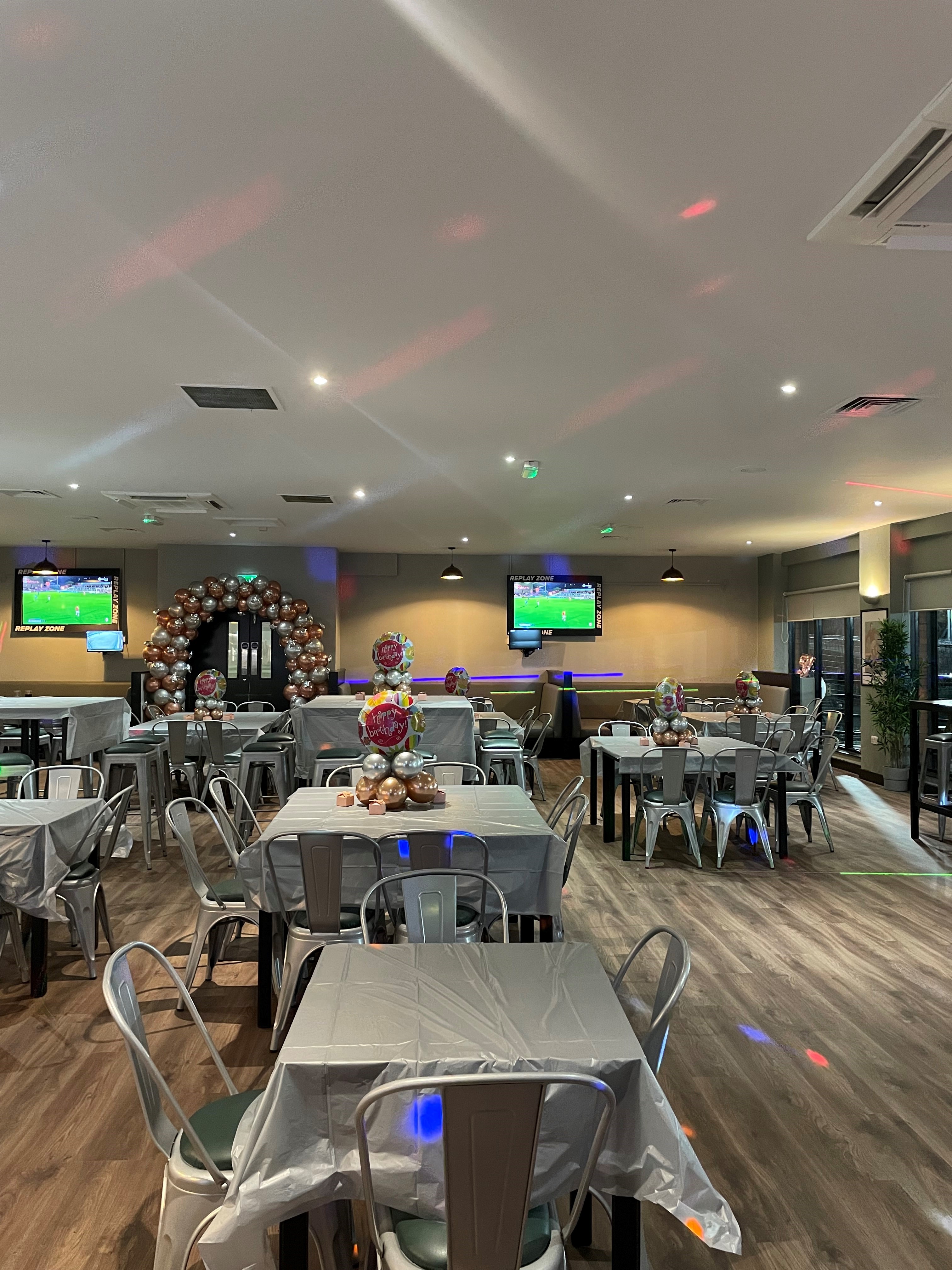 Versatile event space in Powerleague Manchester with silver-dressed tables for gatherings.