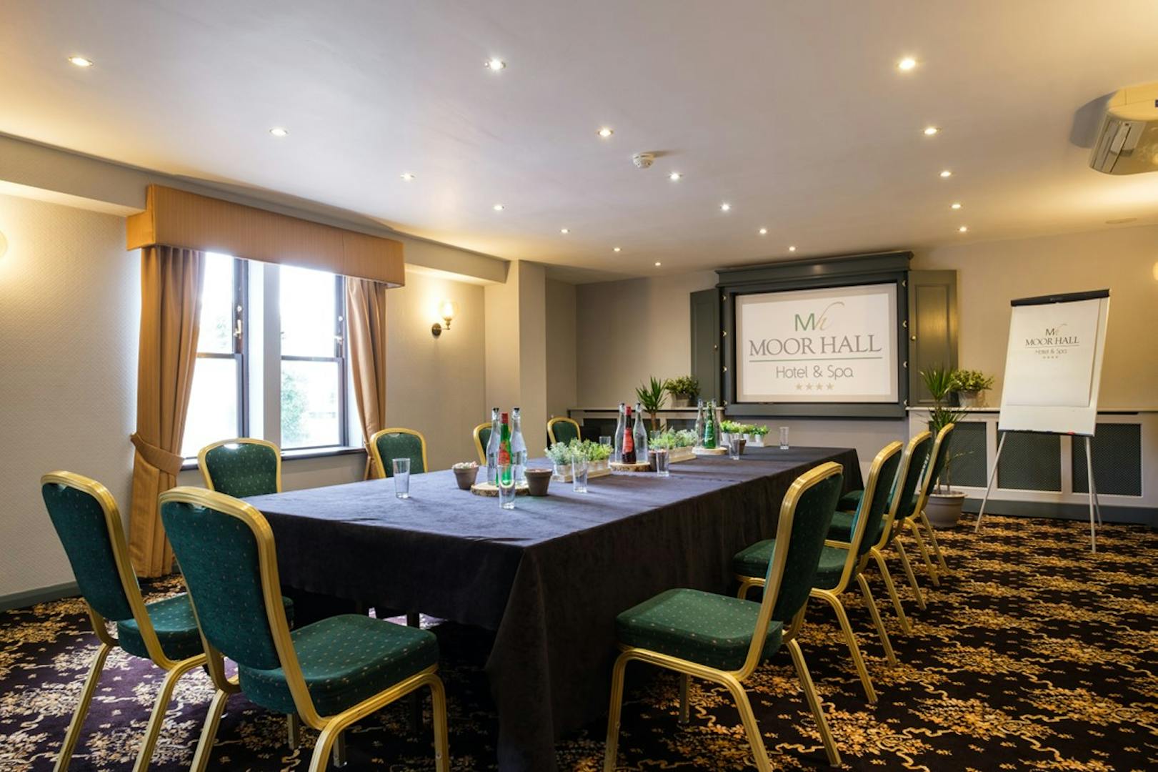 Bracebridge Room at Moor Hall Hotel, elegant meeting space with green chairs and projector.