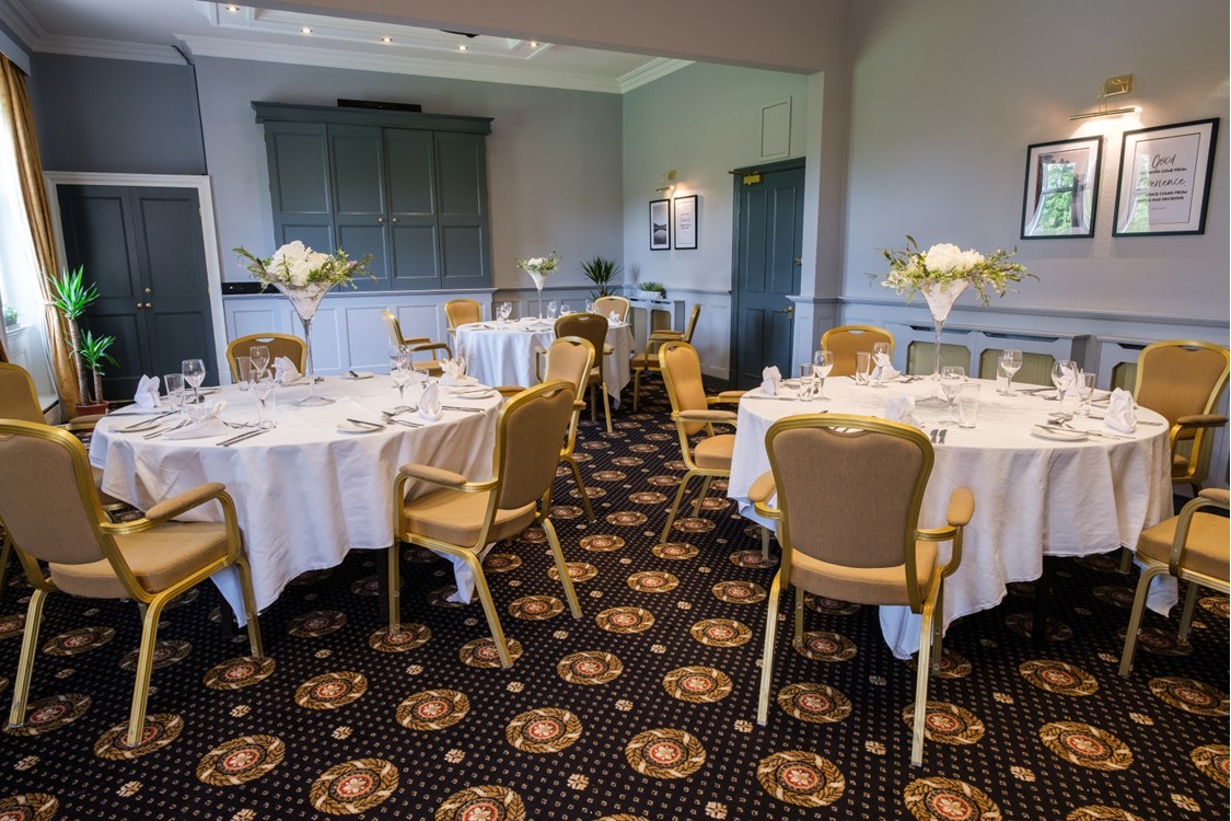 Elegant meeting space at Moor Hall Hotel with round tables and floral centerpieces.