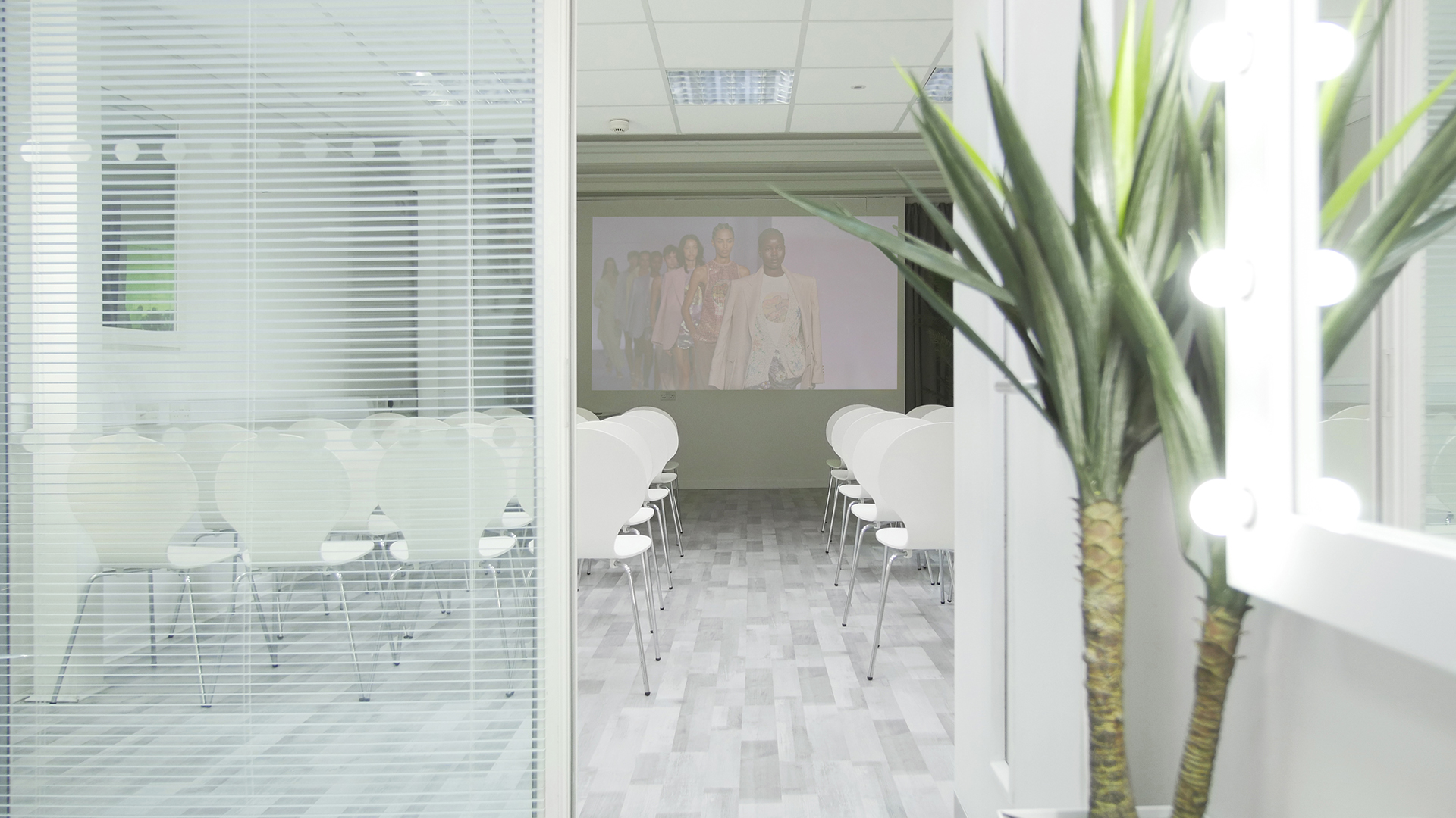 Modern meeting space with white chairs and projection screen for corporate events.