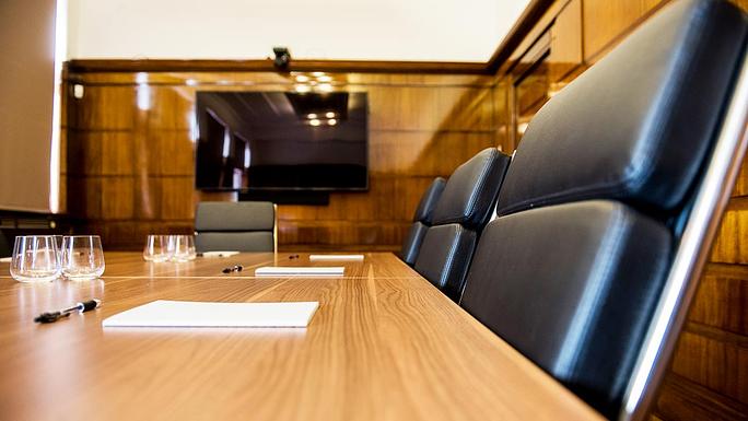 Modern boardroom with polished wooden table, ideal for corporate meetings and presentations.