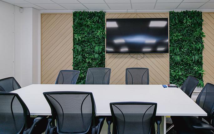 Modern meeting room with large table, greenery, ideal for collaborative events and presentations.