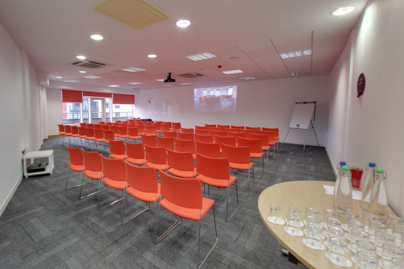 Meeting room at The Studio Leeds with orange chairs, ideal for presentations and events.