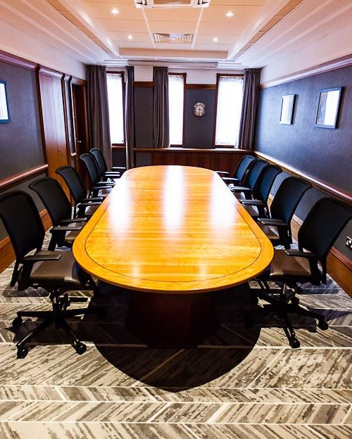 Conference room with wooden table and ergonomic chairs, ideal for meetings and events.