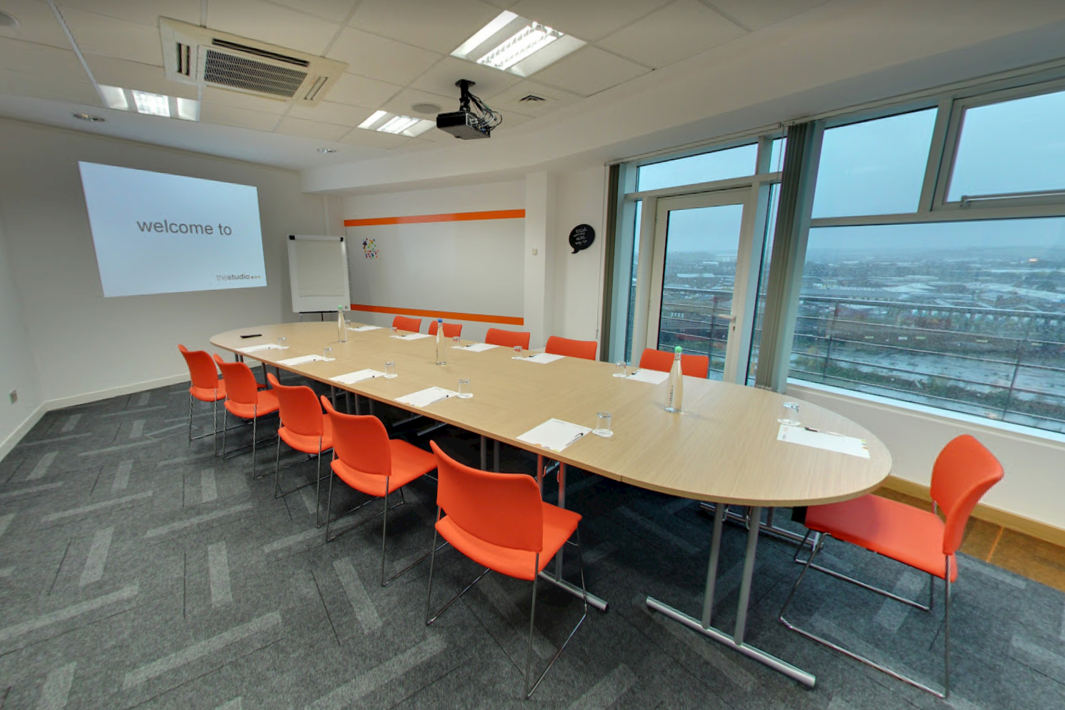 Conference center meeting room with bright orange chairs, ideal for corporate events.