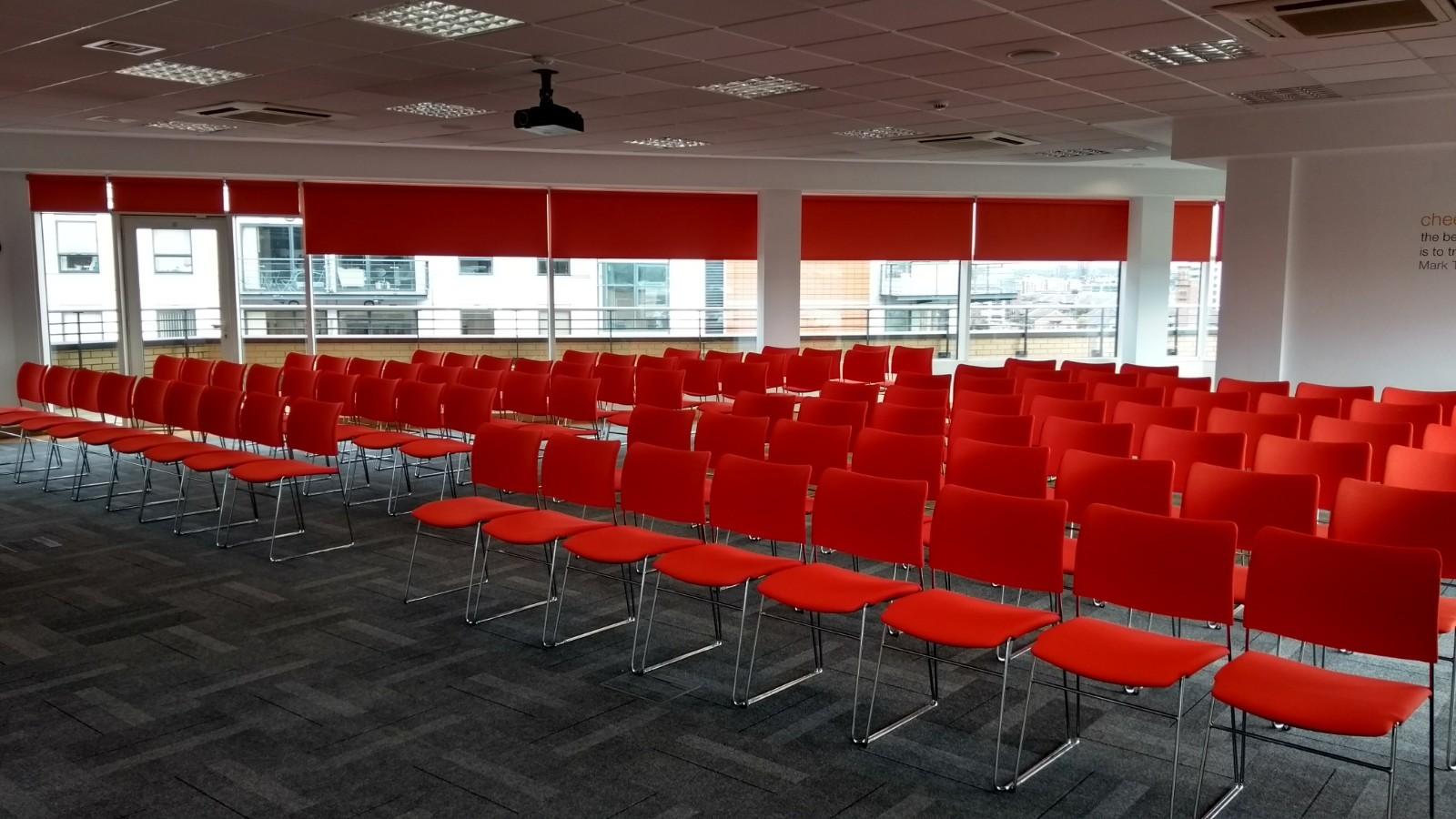 Event space with red chairs and natural light, perfect for seminars and workshops.