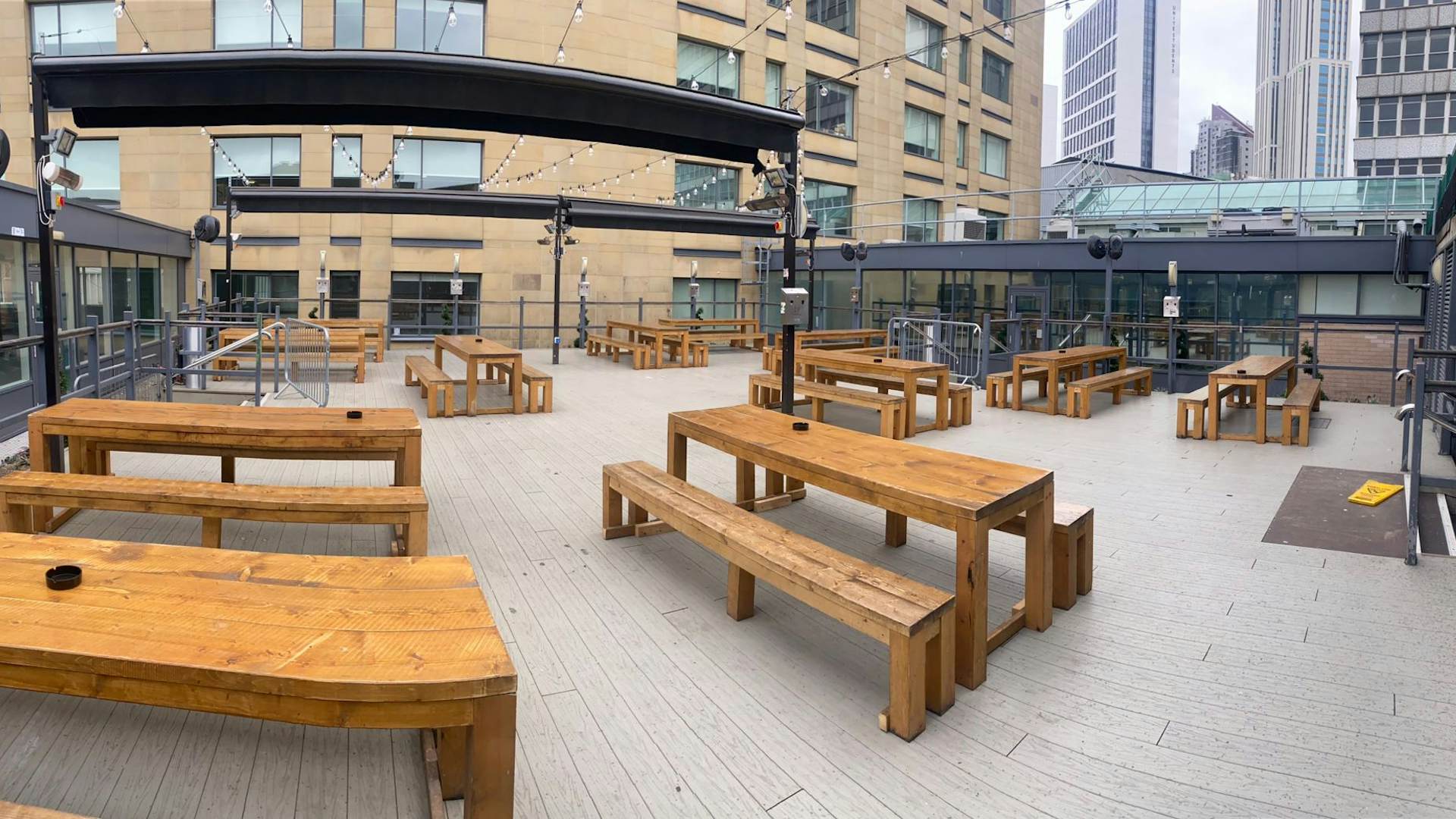 Spacious outdoor event space with wooden benches, ideal for gatherings and networking.