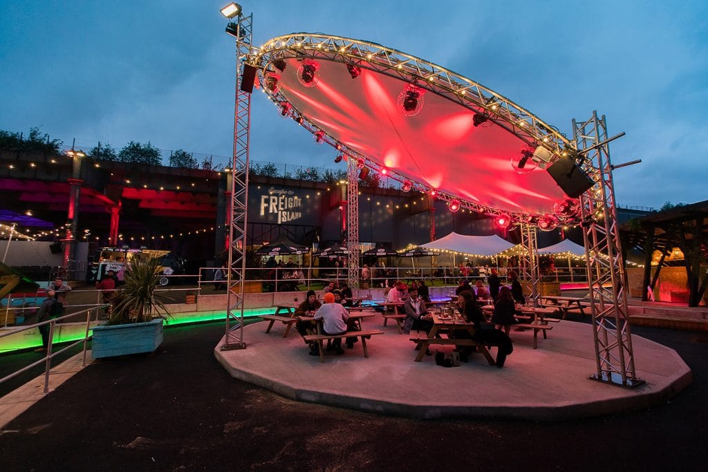 Vibrant outdoor food hall with illuminated stage, perfect for concerts and festivals.
