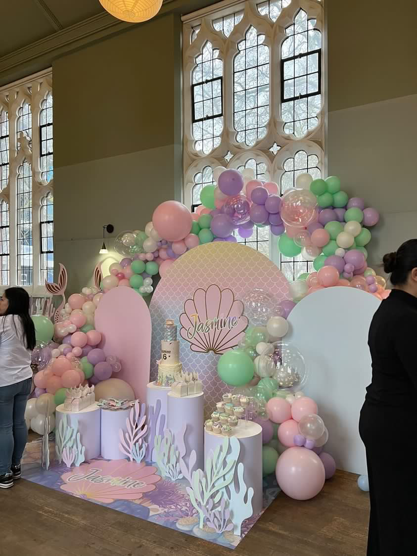 Pastel balloon backdrop with shell motif for birthday or baby shower celebration.