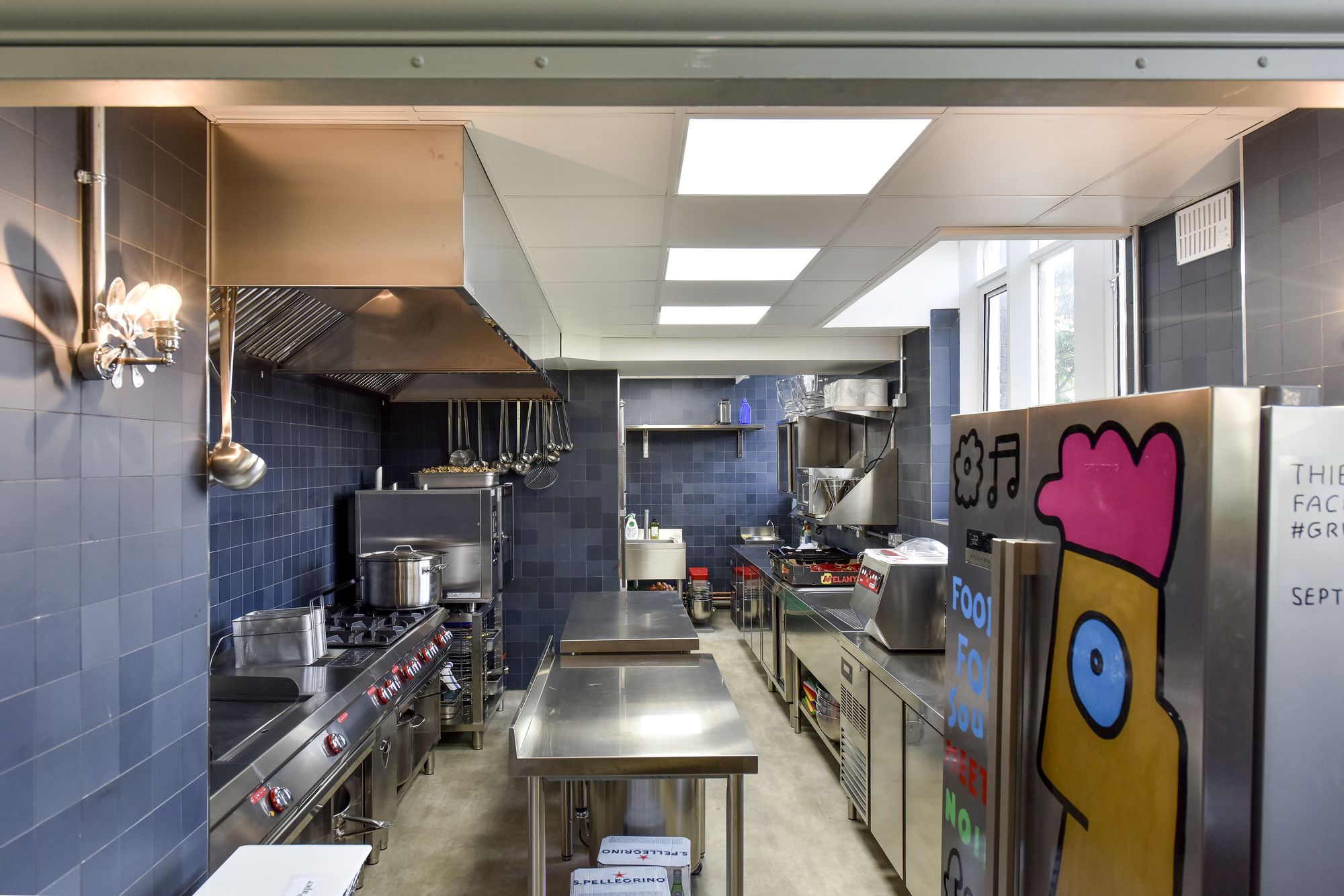 Modern commercial kitchen at Refettorio Felix, featuring stainless steel appliances for events.