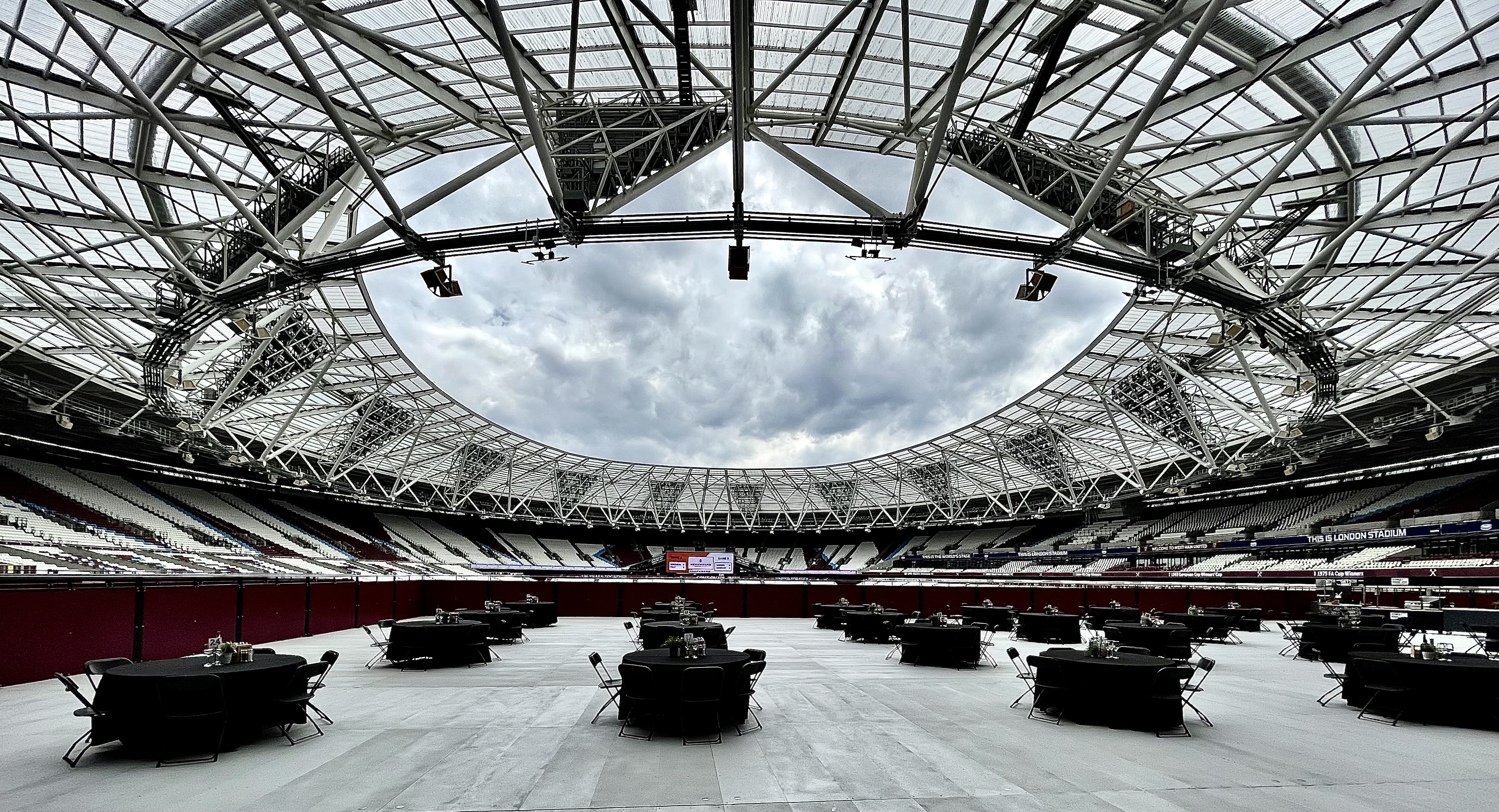 London Stadium's open design, ideal for sports and events, under a dramatic clouded sky.
