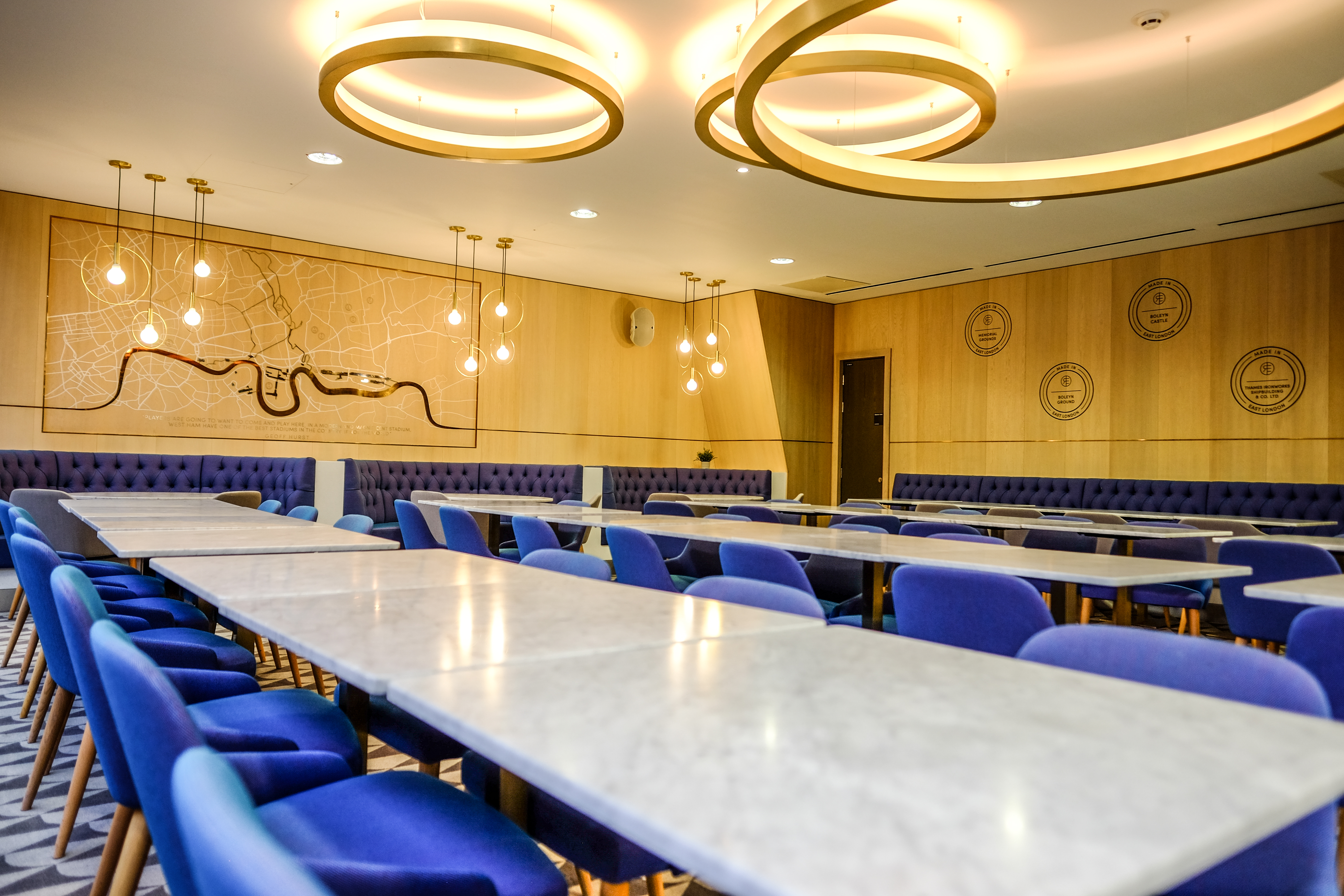 Modern meeting space at The Royal East, featuring marble tables and plush blue chairs.