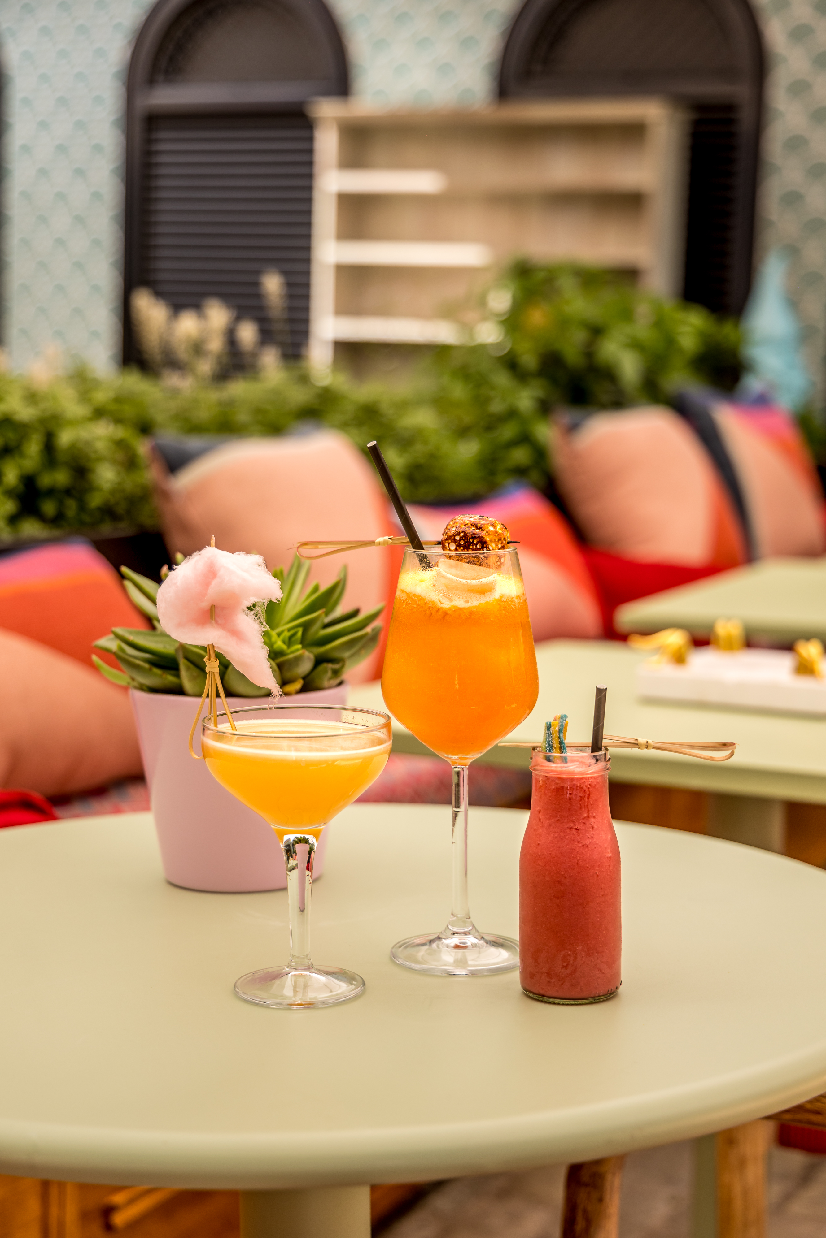 Vibrant cocktails with cotton candy in The Little Scarlet Door courtyard for events.