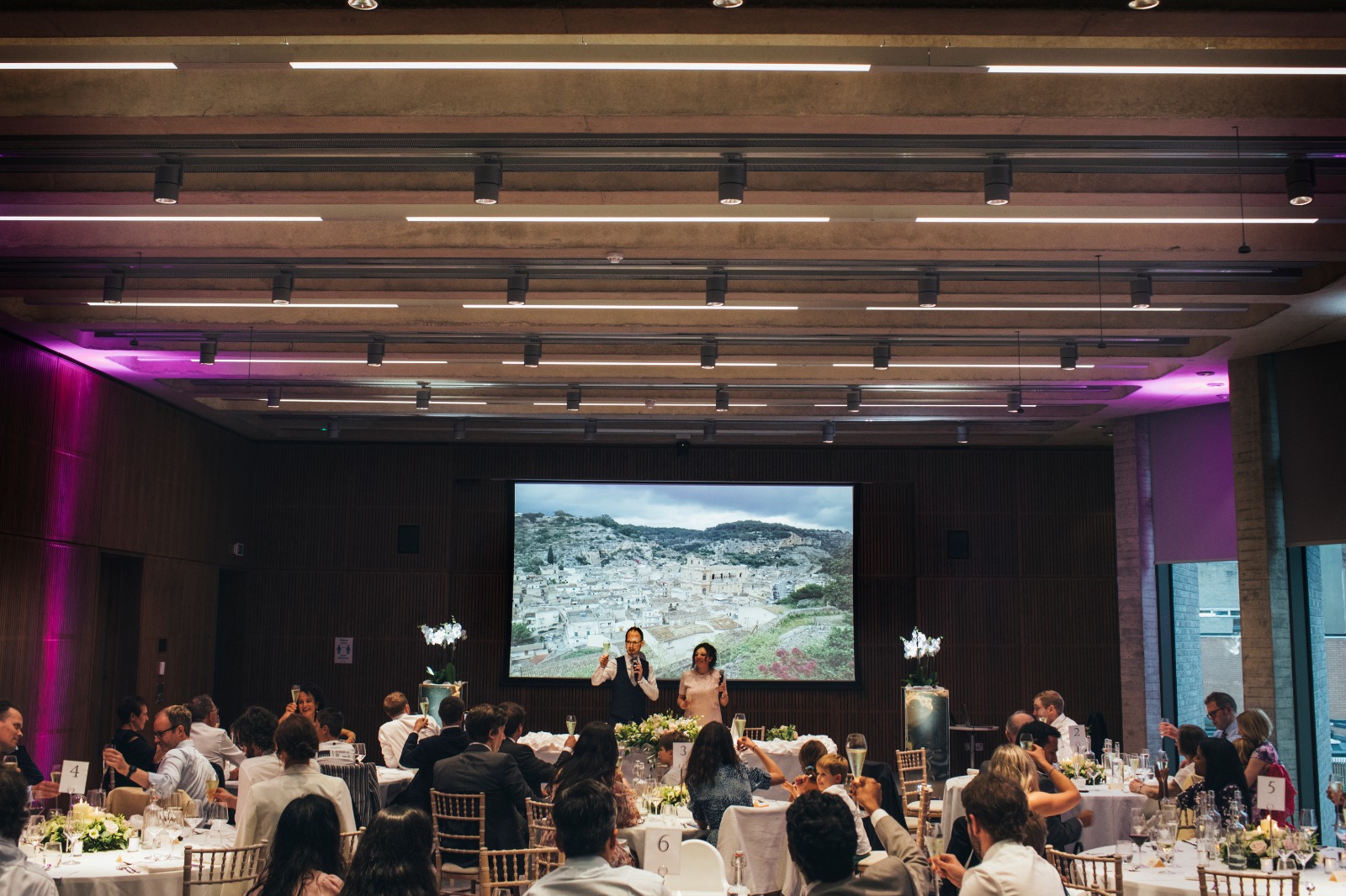 Elegant wedding event space with arranged tables and ambient lighting for networking.