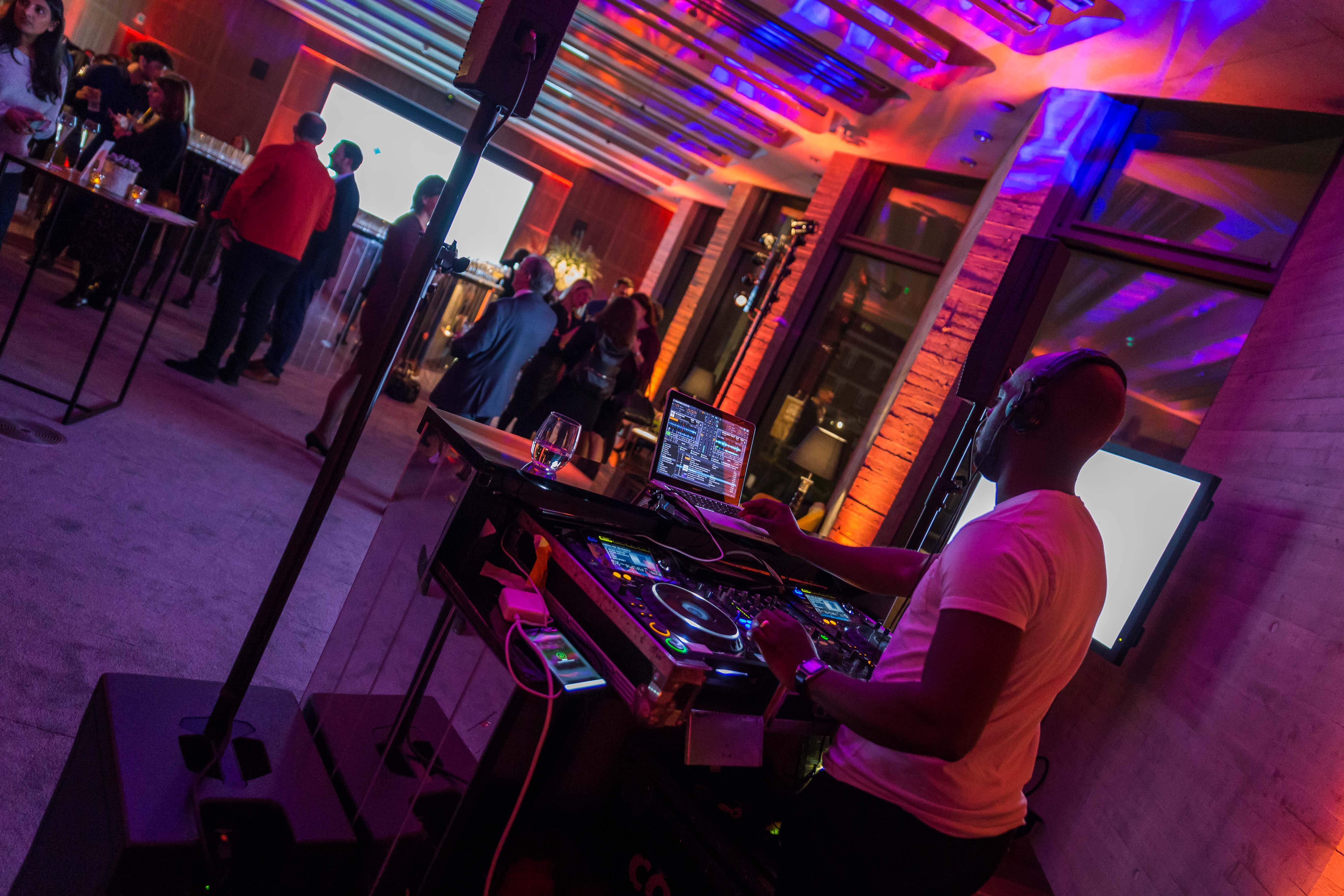 Vibrant wedding event space with DJ and colorful lighting for celebrations and networking.
