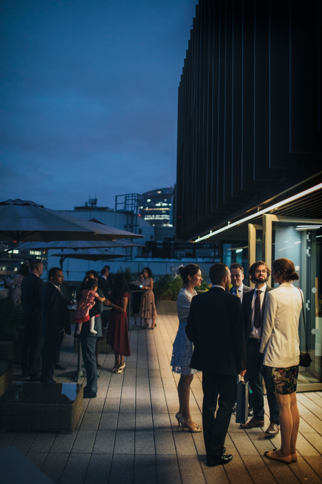 Vibrant rooftop wedding event at dusk with city skyline backdrop, ideal for networking.