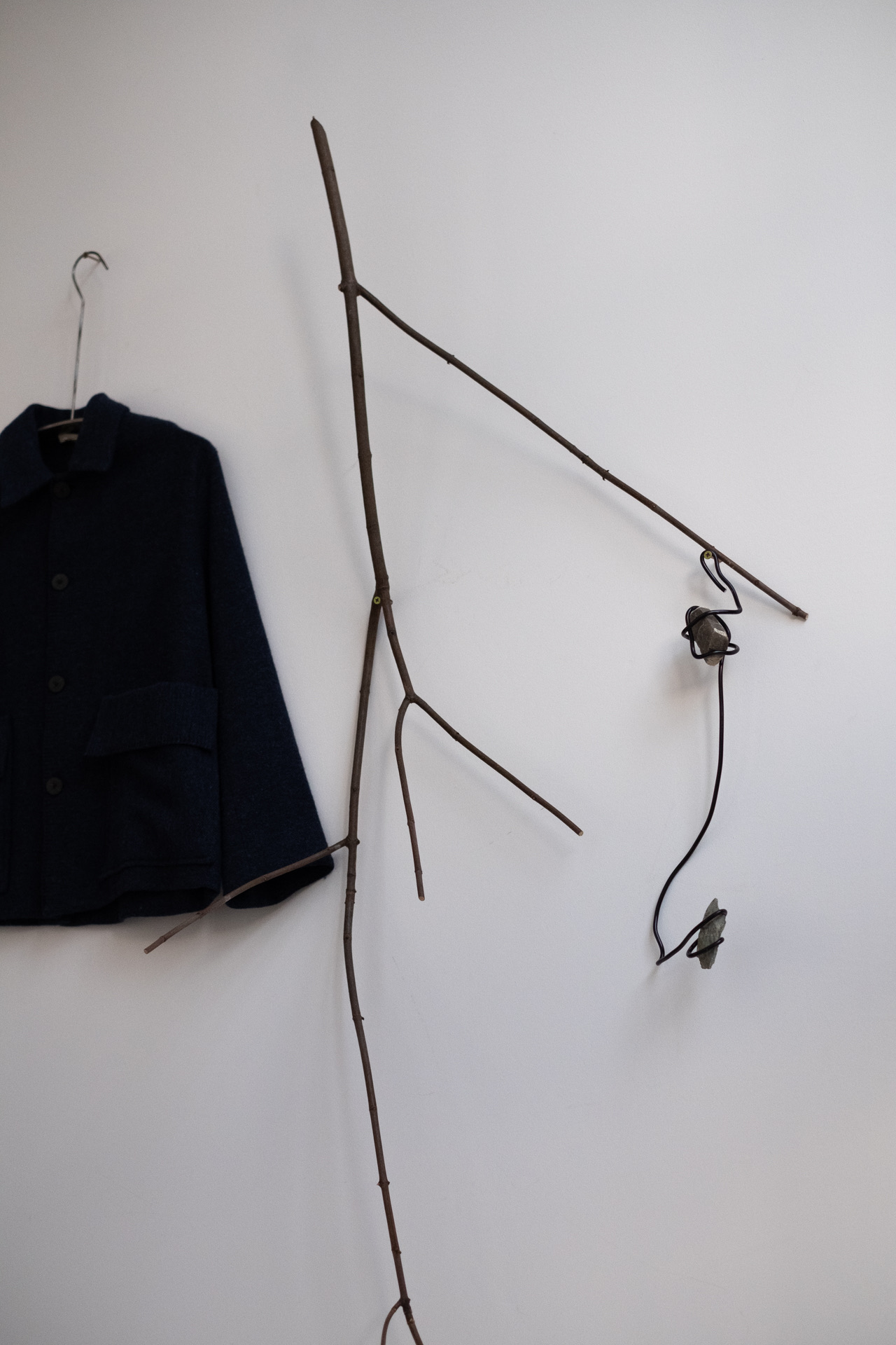 Minimalist event display with dark jacket, rustic branches, and unique lighting in Ensō London.