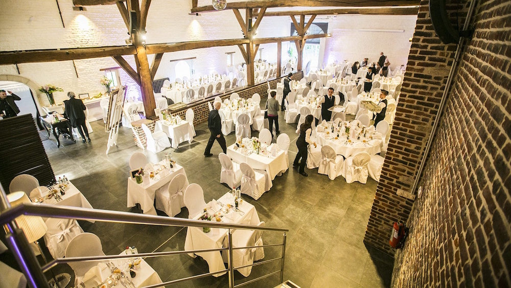 Elegant event space in De Schuur with white linens, perfect for weddings and corporate events.