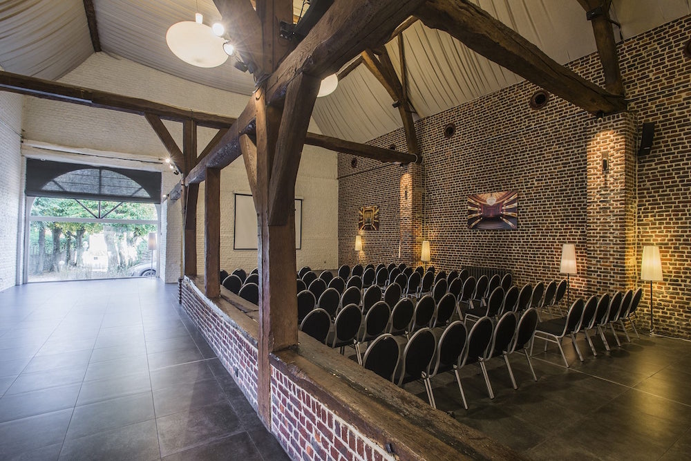 Versatile event space with rustic beams, ideal for meetings and workshops in De Schuur.