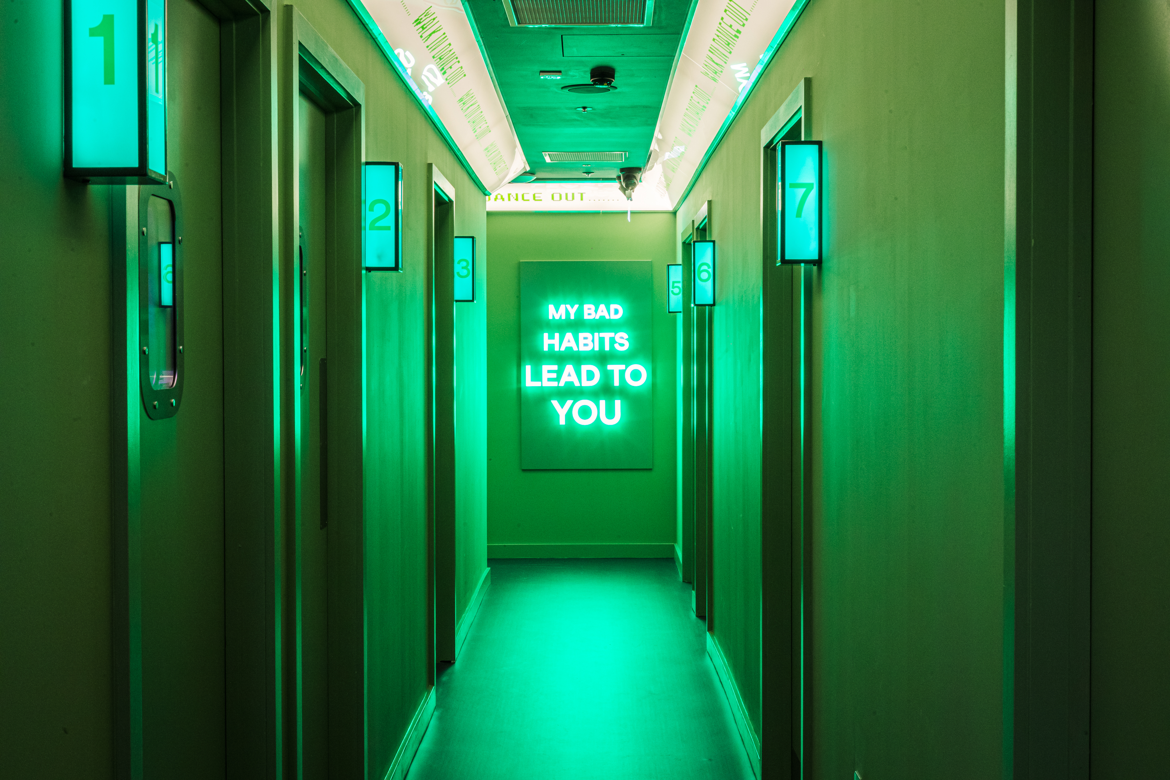 Vibrant green-lit hallway at Lucky Voice Waterloo for summer networking events.