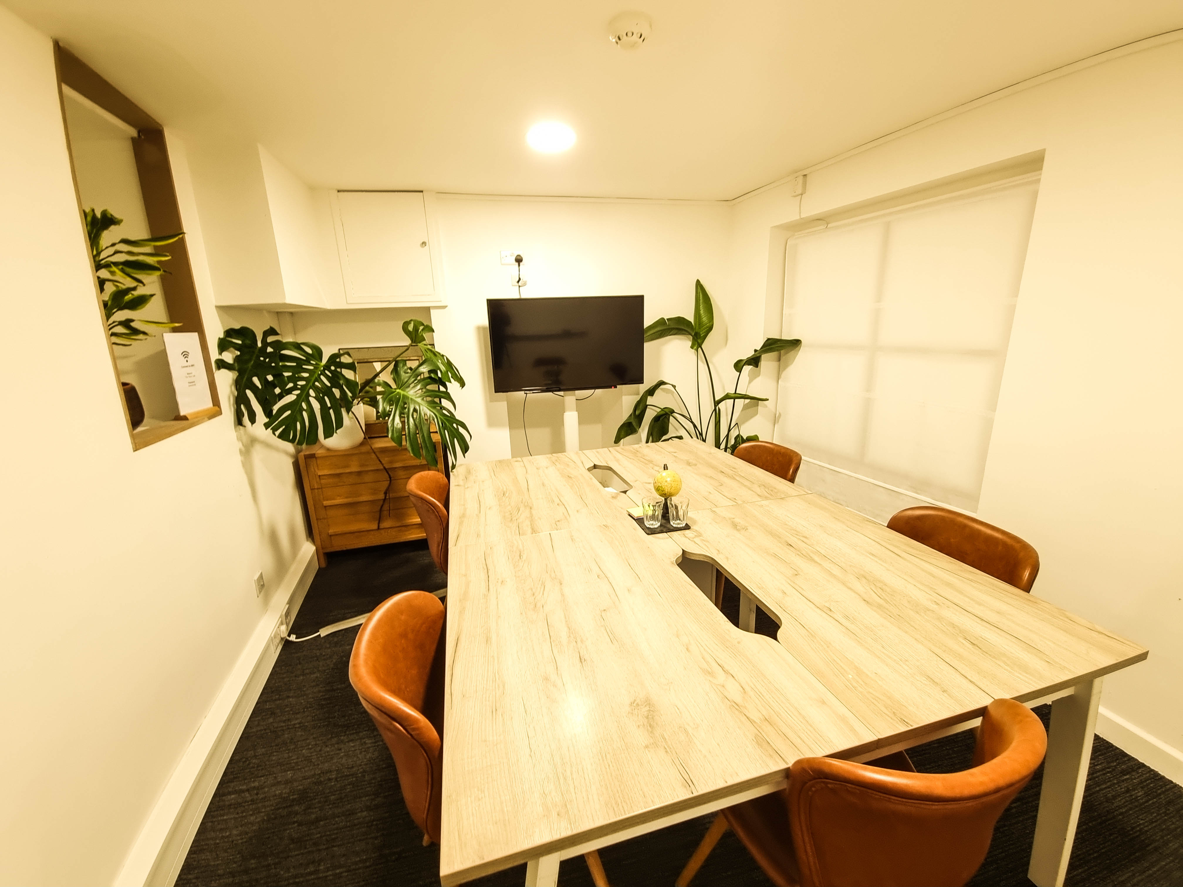 Modern meeting room with wooden table, greenery, ideal for conferences and collaboration.