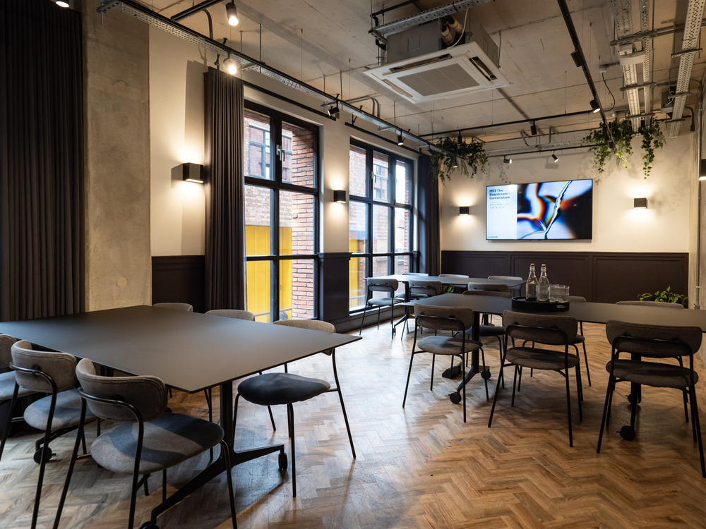 Modern meeting space with modular tables and natural light for corporate events.