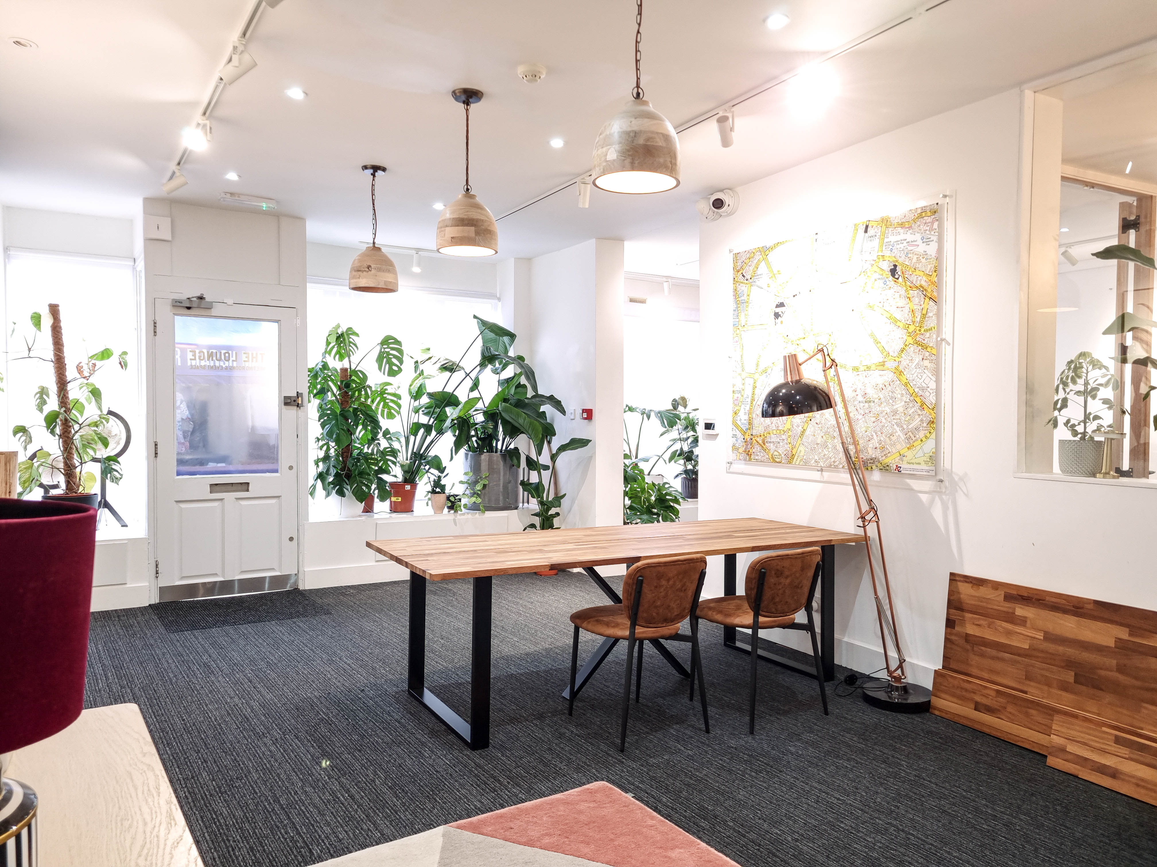 Modern meeting space with wooden table and greenery at The Travel Cafe Lounge.