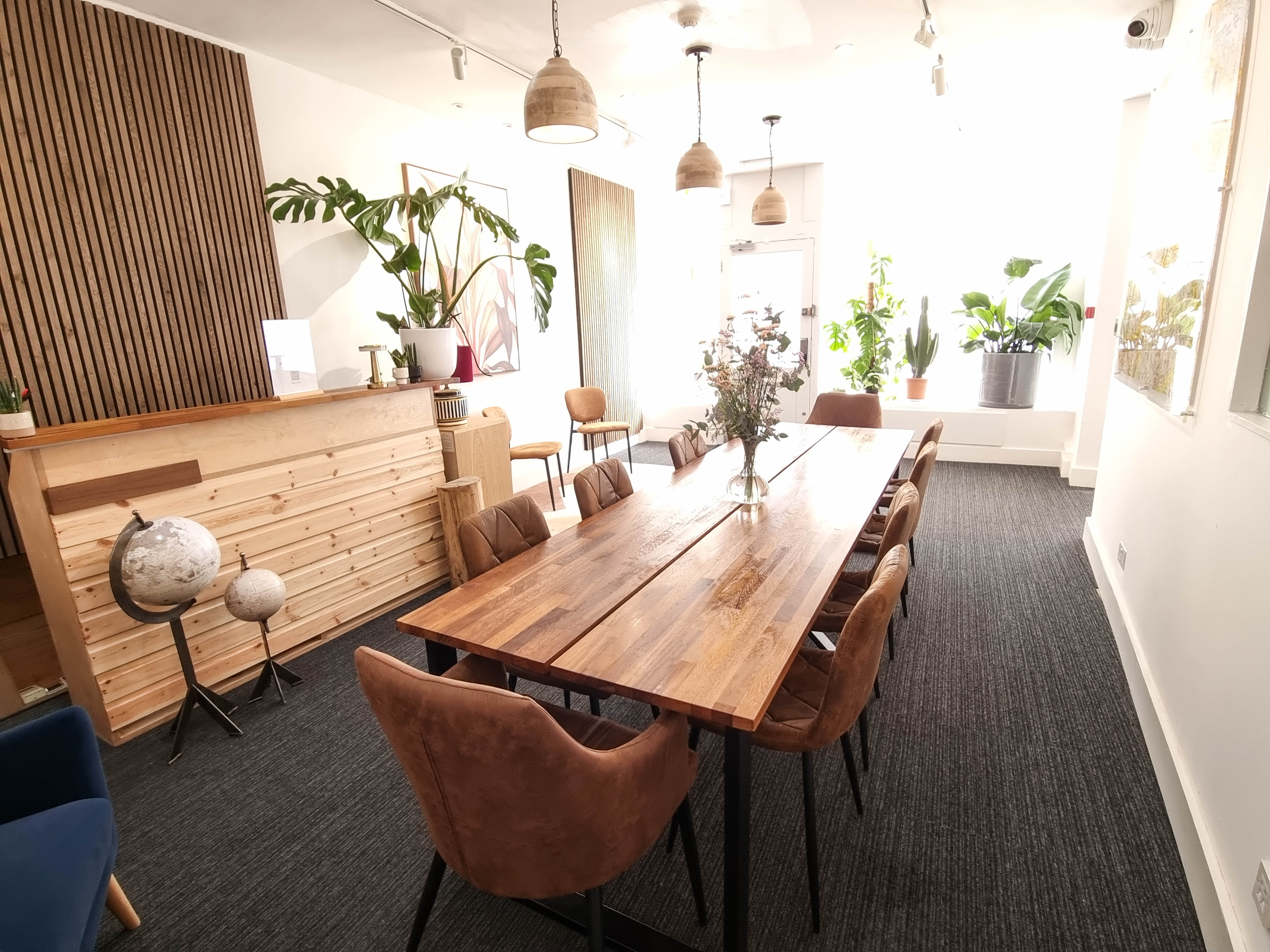 Whole Venue at The Travel Cafe Lounge, featuring a large wooden table for meetings and events.