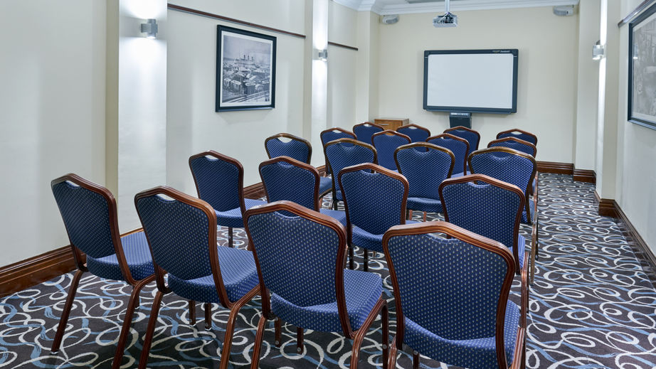 Meeting room with upholstered chairs and projector screen for professional events.