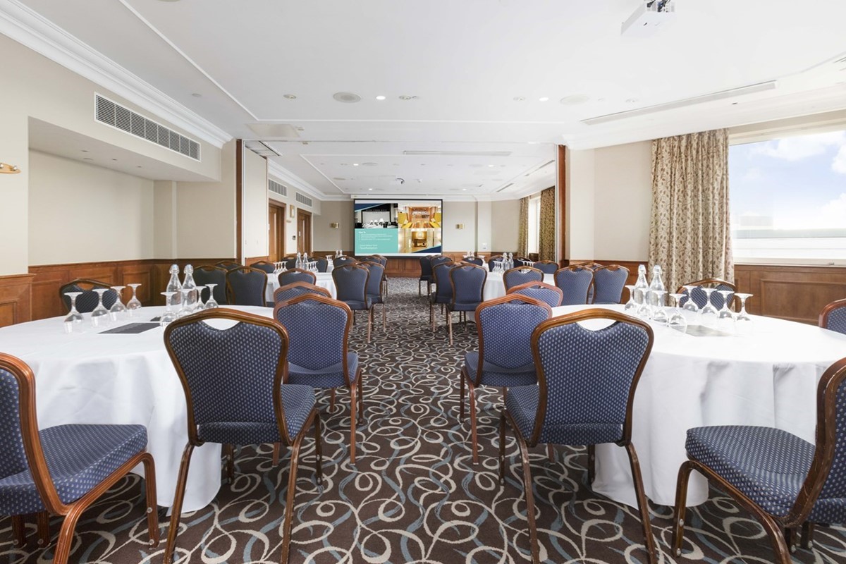 Meeting room with round tables and natural light for corporate events and seminars.