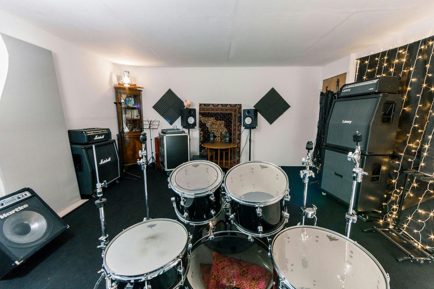 Rehearsal studio with drum set and soundproofing for music events and workshops.