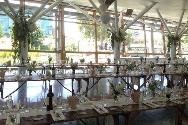 Contemporary glass-walled event space with wooden tables and fresh flowers for gatherings.