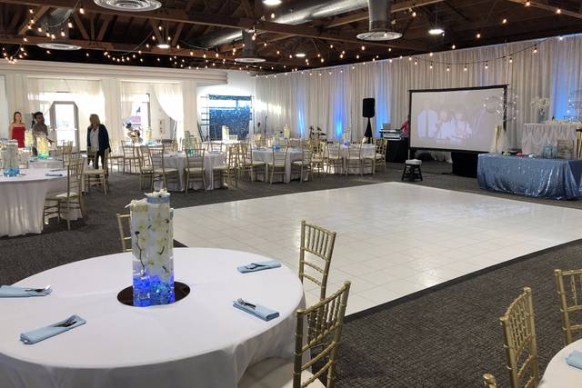 Elegant event space with round tables and soft blue lighting for weddings or corporate gatherings.
