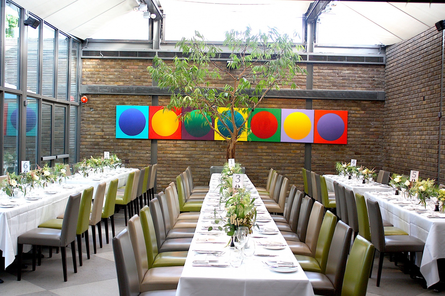 Elegant event space with long dining table under glass ceiling for upscale gatherings.